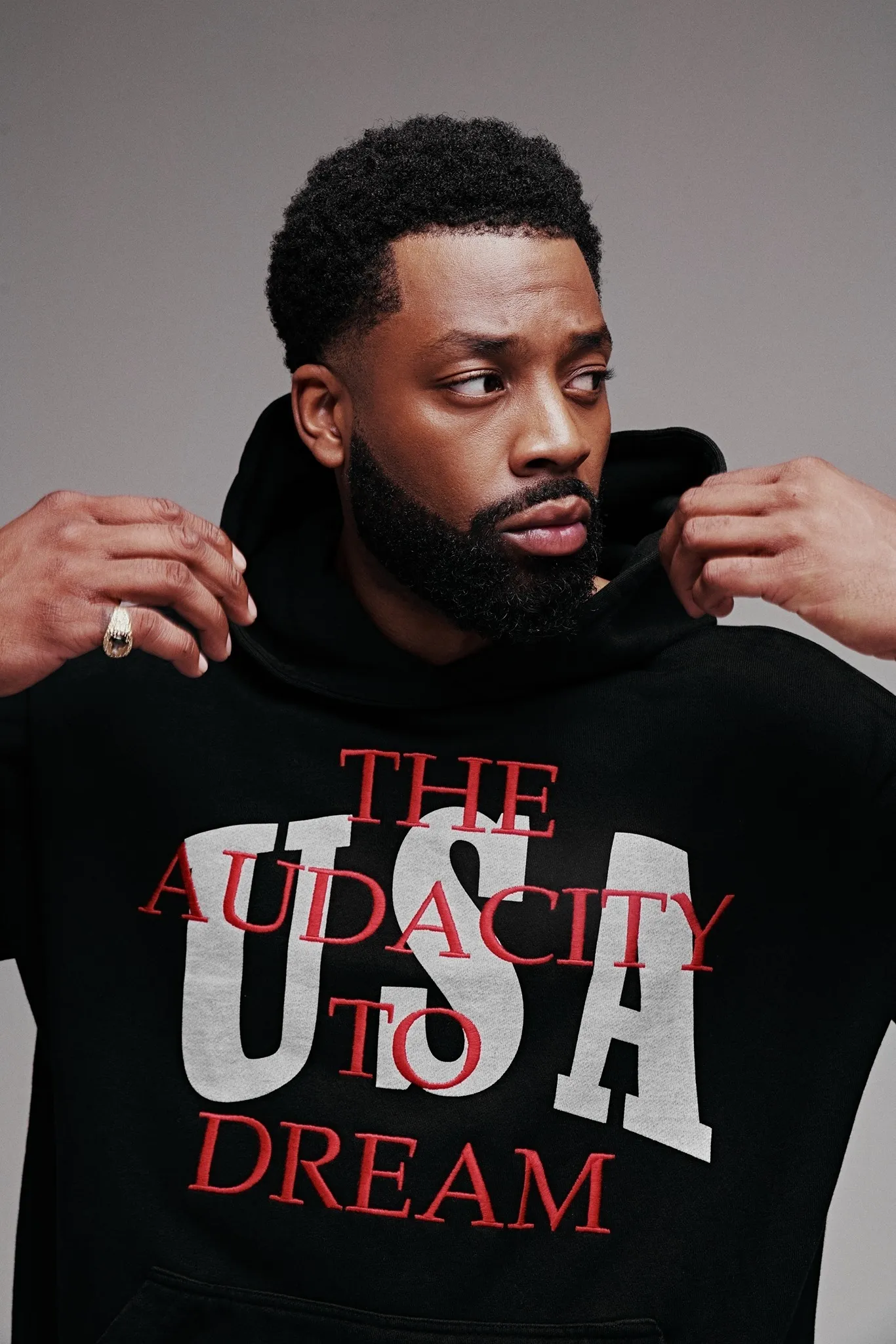 LaRoyce in a black hoodie reading The Audacity to Dream