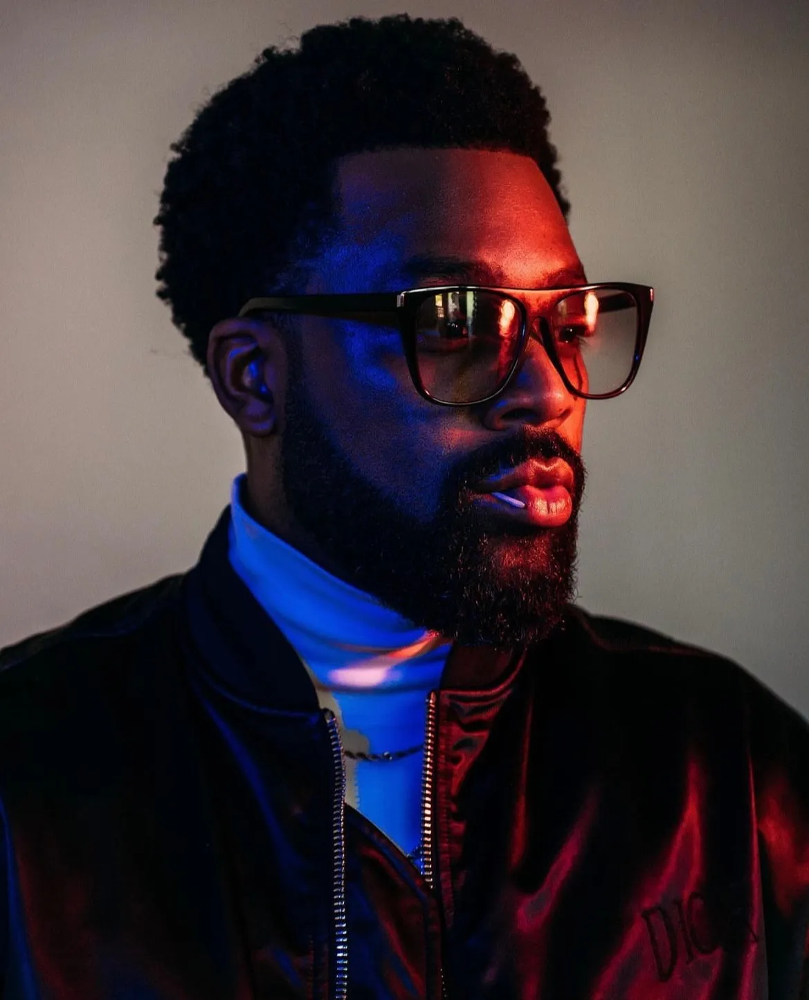 LaRoyce Hawkins in tinted glasses under red and blue light