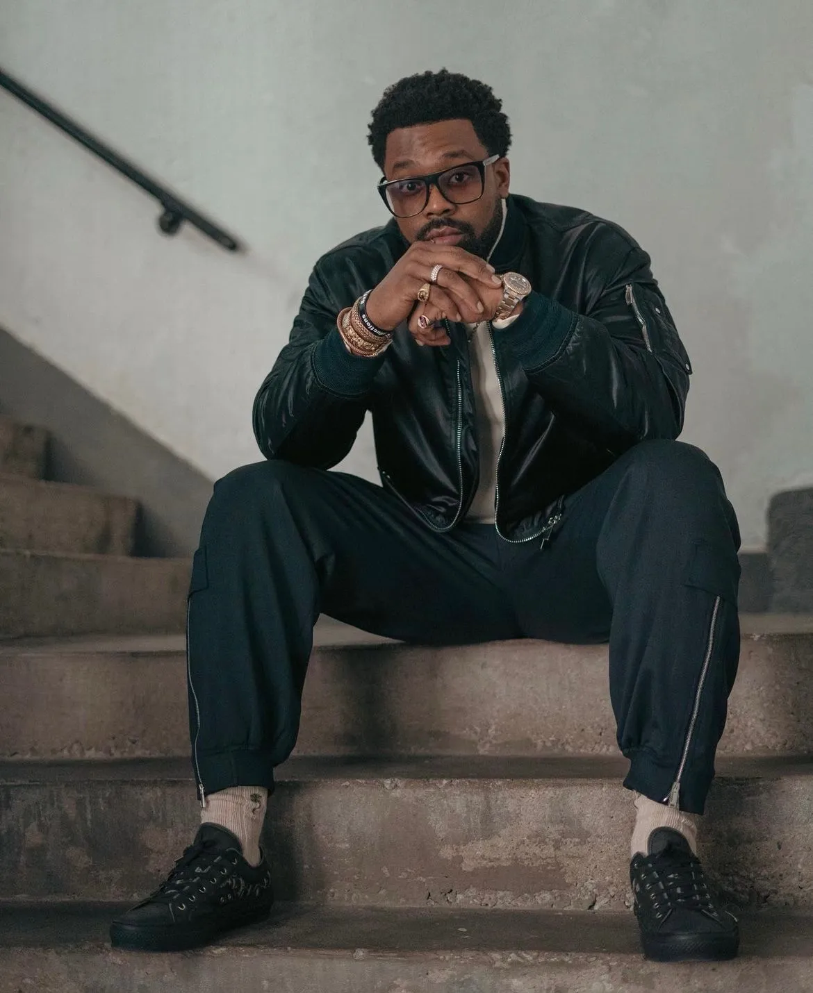 LaRoyce seated on concrete stairs in a dark jacket